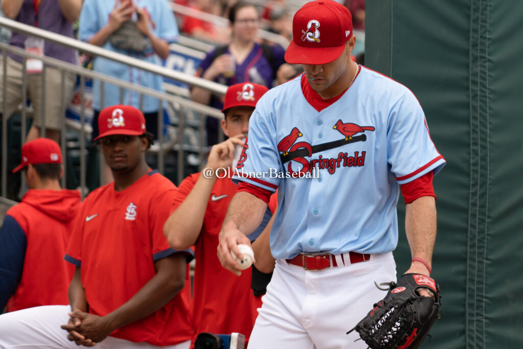 pitcher jack flaherty holds a baseball and looks down while warming up for a start